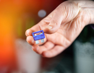 Woman hand holding blue amp rated car fuses before inserting them fuse box closeup shot
