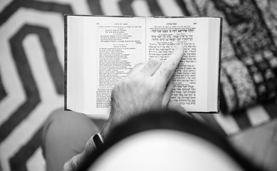 View from above of Jewish male wearing Kippah praying reading Bi-lingual Hebrew French mahzor...