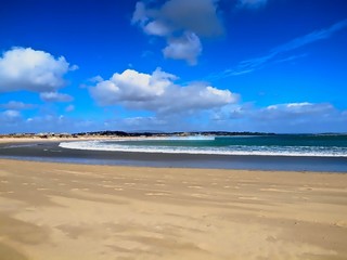 Fototapeta na wymiar Sandstrand am Meer mit blauem Himmel und Wolken