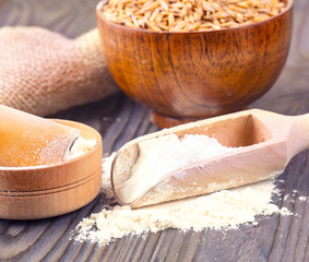 The  flour pile and wheat grains in wooden spoon and bowl