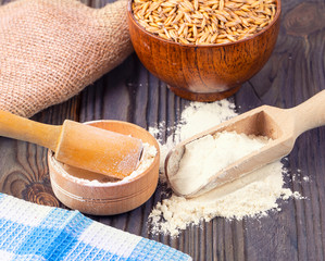The  flour pile and wheat grains in wooden spoon and bowl