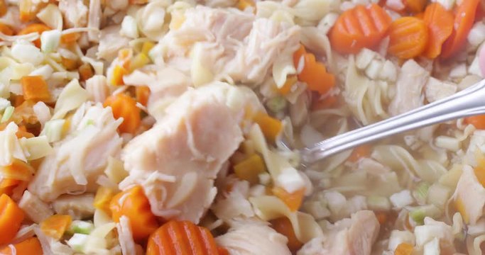 Close Video Of Stirring Home Made Chicken Noodle Soup With A Spoon Then Taking A Spoonful At The End.