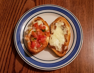 Molletes made of sliced bolillo bread with grilled cheese and refried beans, frijoles refritos. Accompanied with pico de gallo. Delicious traditional Mexican food.