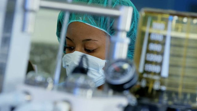 Professional Multi ethnic female Anesthesiologist monitoring anesthesia machine equipment during patient operation in hospital theater 