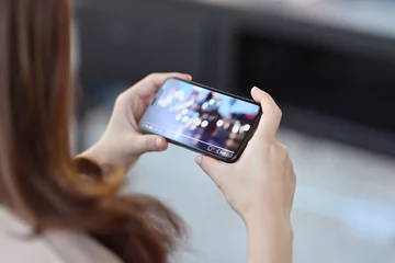 Foto op Plexiglas Cropped shot of female hand holding mobile phone playing video stream online © bongkarn