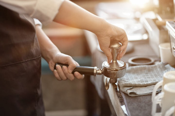 Waitress or Barista tamper while using a coffee machine