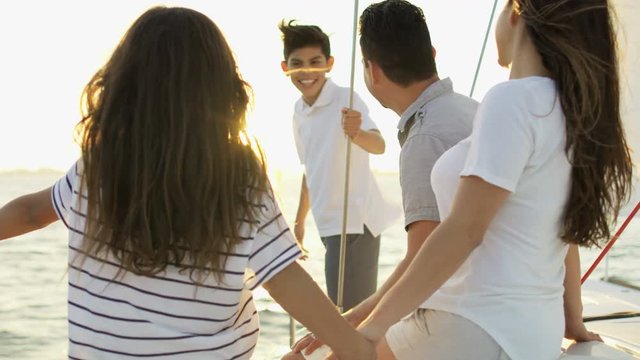 Young Ethnic Latino Family On Vacation Enjoying Carefree Lifestyle Sailing The Ocean On Luxury Yacht Sun Flare 