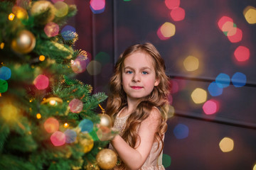 Fototapeta na wymiar Little girl under the Christmas tree. A girl with gifts under the tree in anticipation of magic