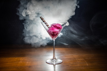 Martini glass filled with colorful fruit ice cream on dark background with toned light and fog