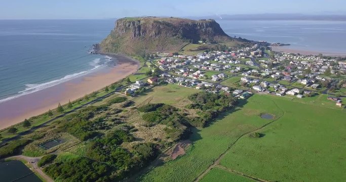 Aerial flight over town with huge rock in background in Tasmania, Australia