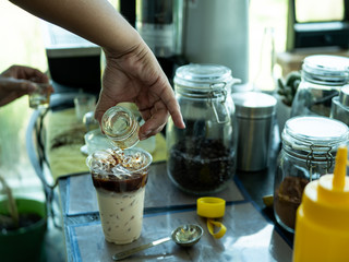 Hand of Barista preparing cappuccino with iced coffee