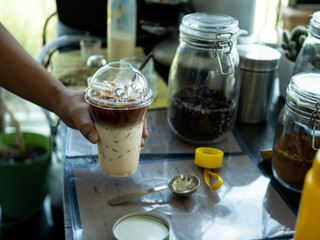 Hand of Barista preparing cappuccino with iced coffee