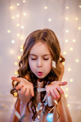 Portrait of a little girl with curly hair on Christmas Eve, the New Year will bring gifts.