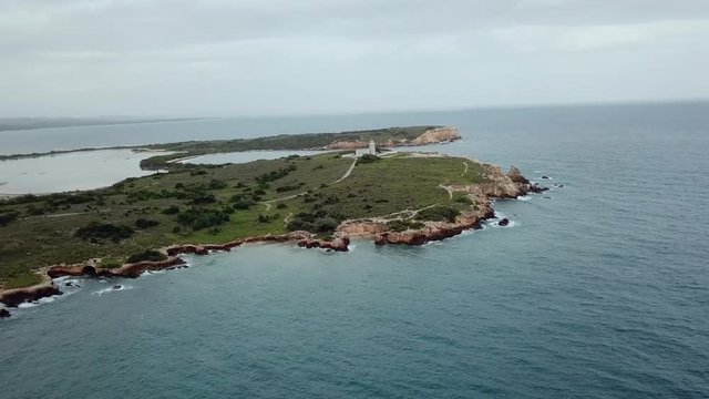 Slow push towards the peninsula of Cabo Rojo, with a lighthouse, high above the terrain and over the ocean.