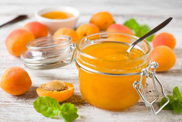 jar with homemade apricot jam on a light wooden background