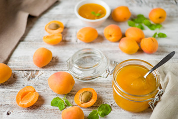 jar with homemade apricot jam on a light wooden background