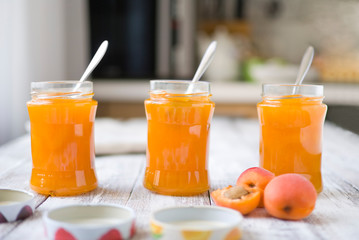 jar with homemade apricot jam on a light wooden background