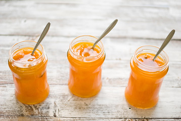 jar with homemade apricot jam on a light wooden background