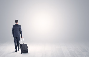 Young businessman in a white boundless space walking with back and luggage on his hand