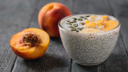 Ripe peach fruit and Chia seed pudding on a dark wooden table.
