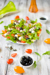 Arugula salad \ Salad with rocket salad, cherry, olives, cheese, mozzarella, blue cheese, sausage on a light wooden background