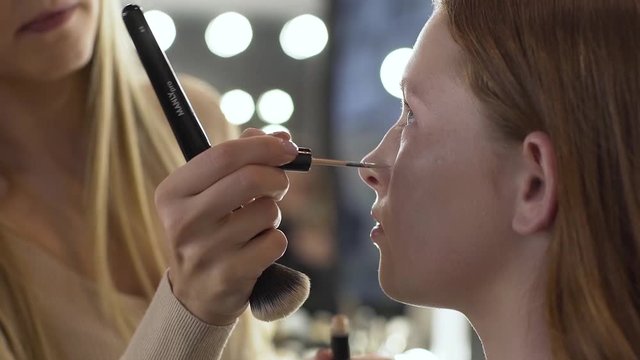 Makeup artist applying make-up on face of model