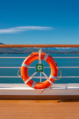 Bright orange life preserver in white metal holder aboard ship, Alaska, USA.