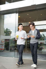 Two smiling businessmen walking and talking in the city