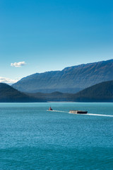 Tugboat pulling barge on a sunny day. Gastineau Channel, Juneau, Alaska, USA.