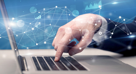 Businessman typing on laptop with linked reports charts grapghs around
