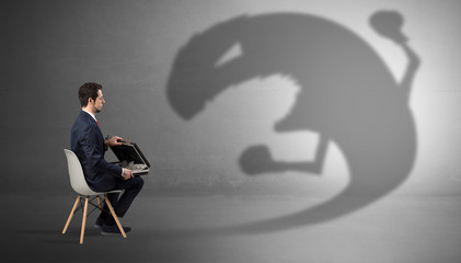 Young businessman staying and  negotiate with a monster shadow
