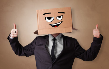 Young man with happy face illustrated cardboard box on his head
