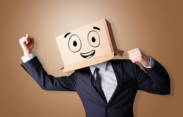Young man standing and gesturing with a cardboard box on his head with drawn smiley face
