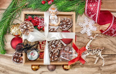 Fototapeta na wymiar Christmas gifts in a wooden box on a wooden background. Christmas tree branches, decorations, cones, angel and gifts.