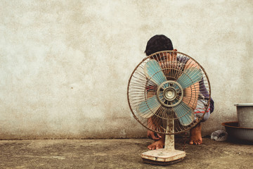 Young boy hiding behind an old electrical fan