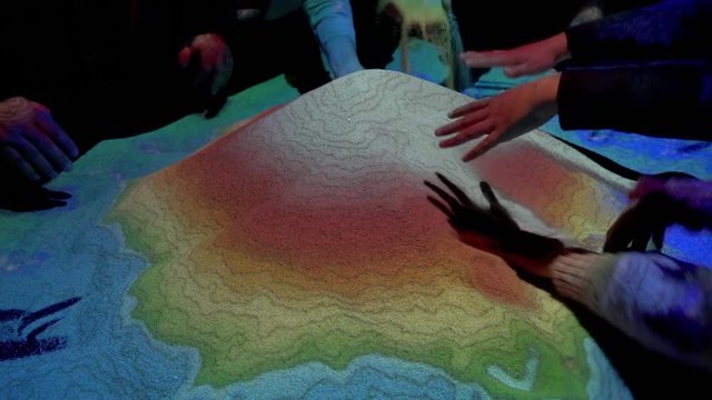 People playing with an augmented reality sandbox.