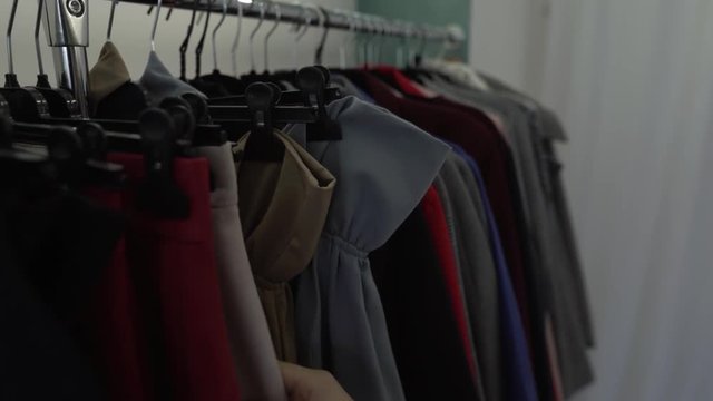 Female hand is touching different classic winter clothes pausing on some items in the shop. Close-up concept