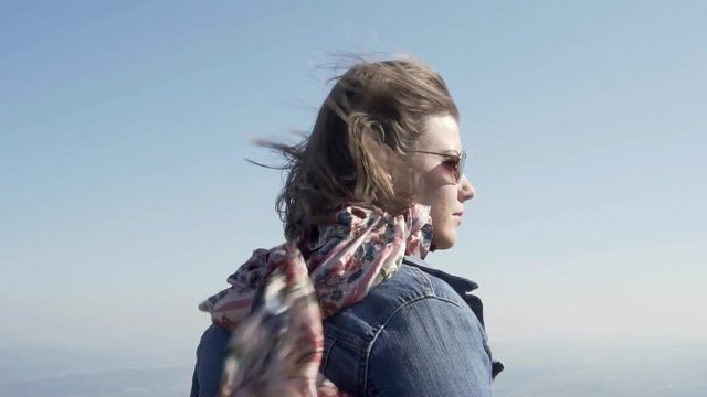 Profile shot of a young woman in strong wind with clear blue sky, slow motion.