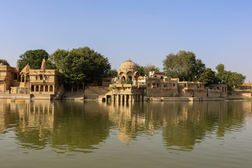 Fototapeta na wymiar A man-made water reservoir (Gadisar Lake) in Jaisalmer. Constructed by the first ruler of Jaisalmer, Raja Rawal Jaisal, it is surrounded by temples and ghats (banks).