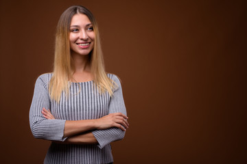 Obraz premium Studio shot of young beautiful woman thinking against brown background