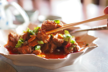 Spicy stir-fried pork on chopsticks