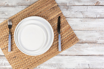 empty white dishes (plate, bowl) on a white wooden background (table), top view, copy space, mock-up