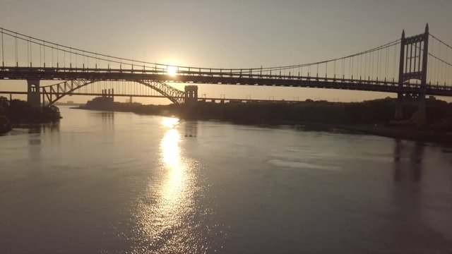 Aerial rising crane shot of RFK and Hell's Gate bridge with sunrise