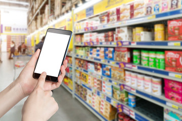 Female hand holding mobile smart phone on Supermarket blur background, business concept