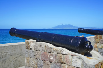 View of a colonial cannon pointed towards the Caribbean Sea in Charlestown, the capital of Nevis in the Federation of St Kitts and Nevis in the West Indies