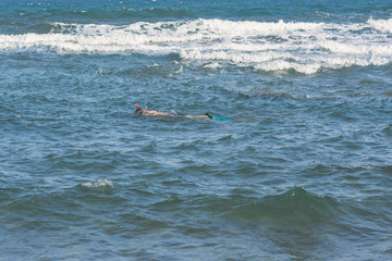 Man dives in the swimming flippers snorkeling mask and tube in the storm waves. The concept of sports and healthy lifestyle