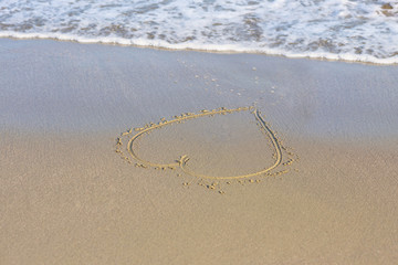 Painted shape of the heart on the sand on the beach .  Travel concept
