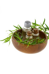 Tarragon essential oil set in glass bottles and  green twigs of tarragon in a round wooden cup...