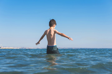 Fototapeta premium Teen boy in the wave of the sea on the beach 