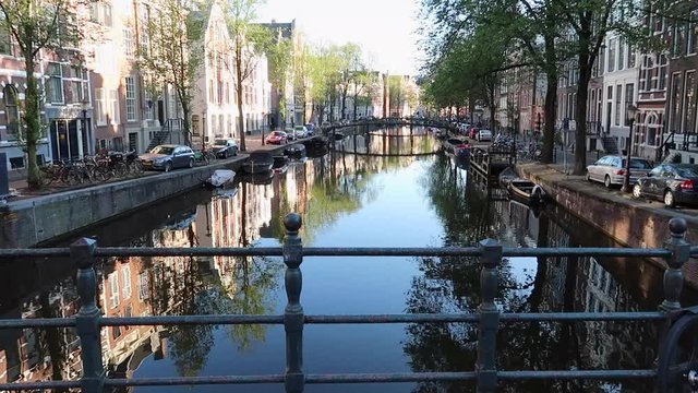 Beautiful landscape of a canal in Amsterdam with houses and cars on the edge over a bridge. Netherlands. Flat plane